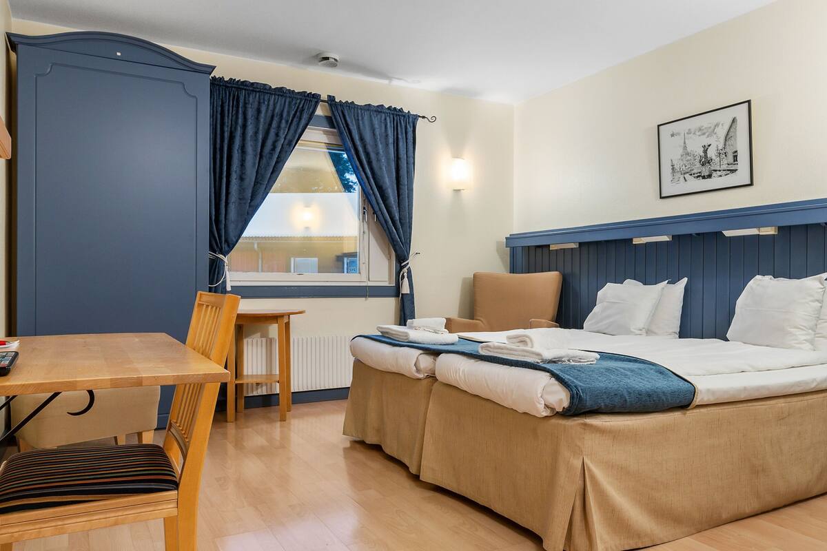 A hotel room with a bed, a desk, and a chair.