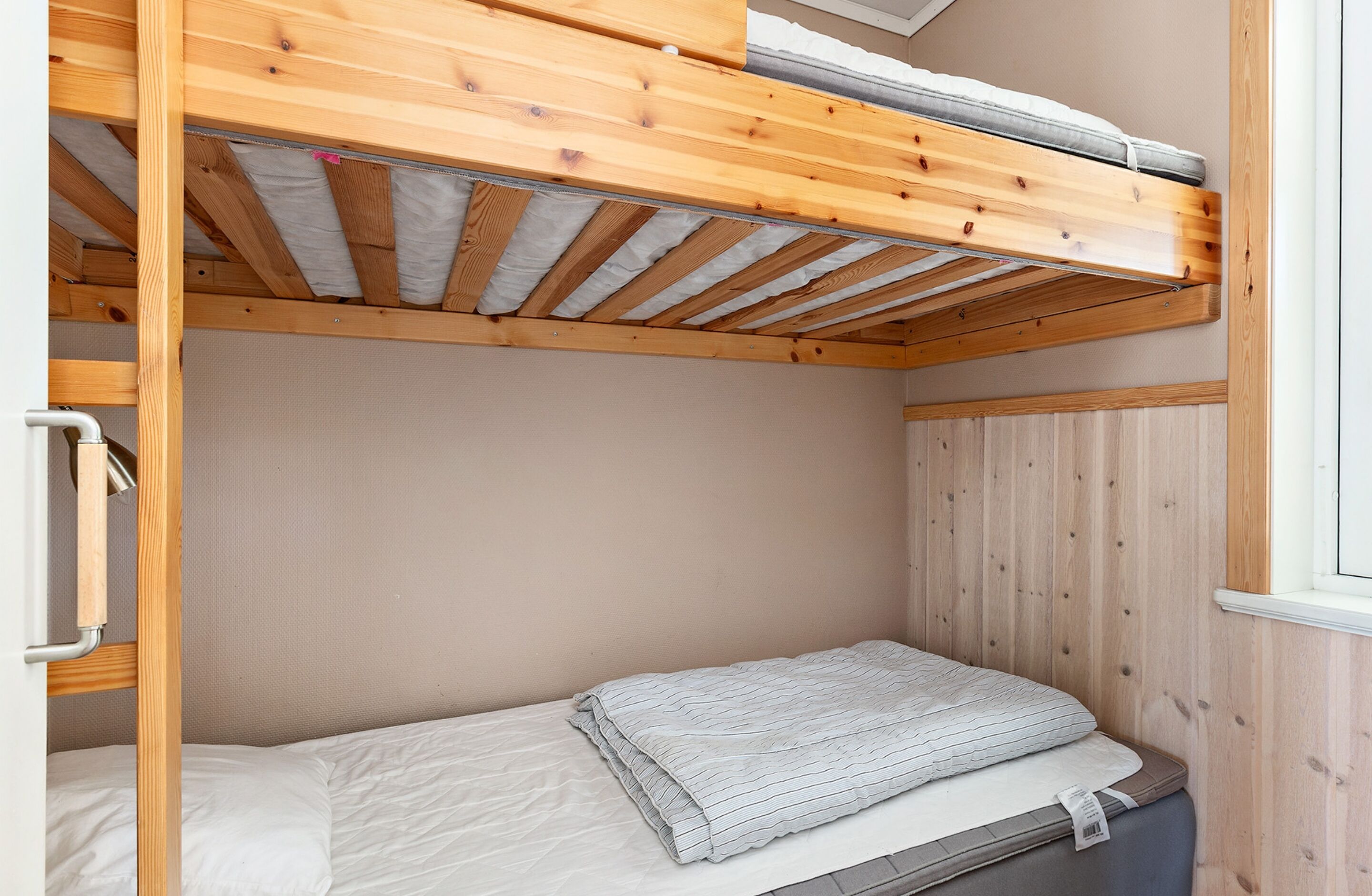 Una litera de madera con colchón y manta a rayas.