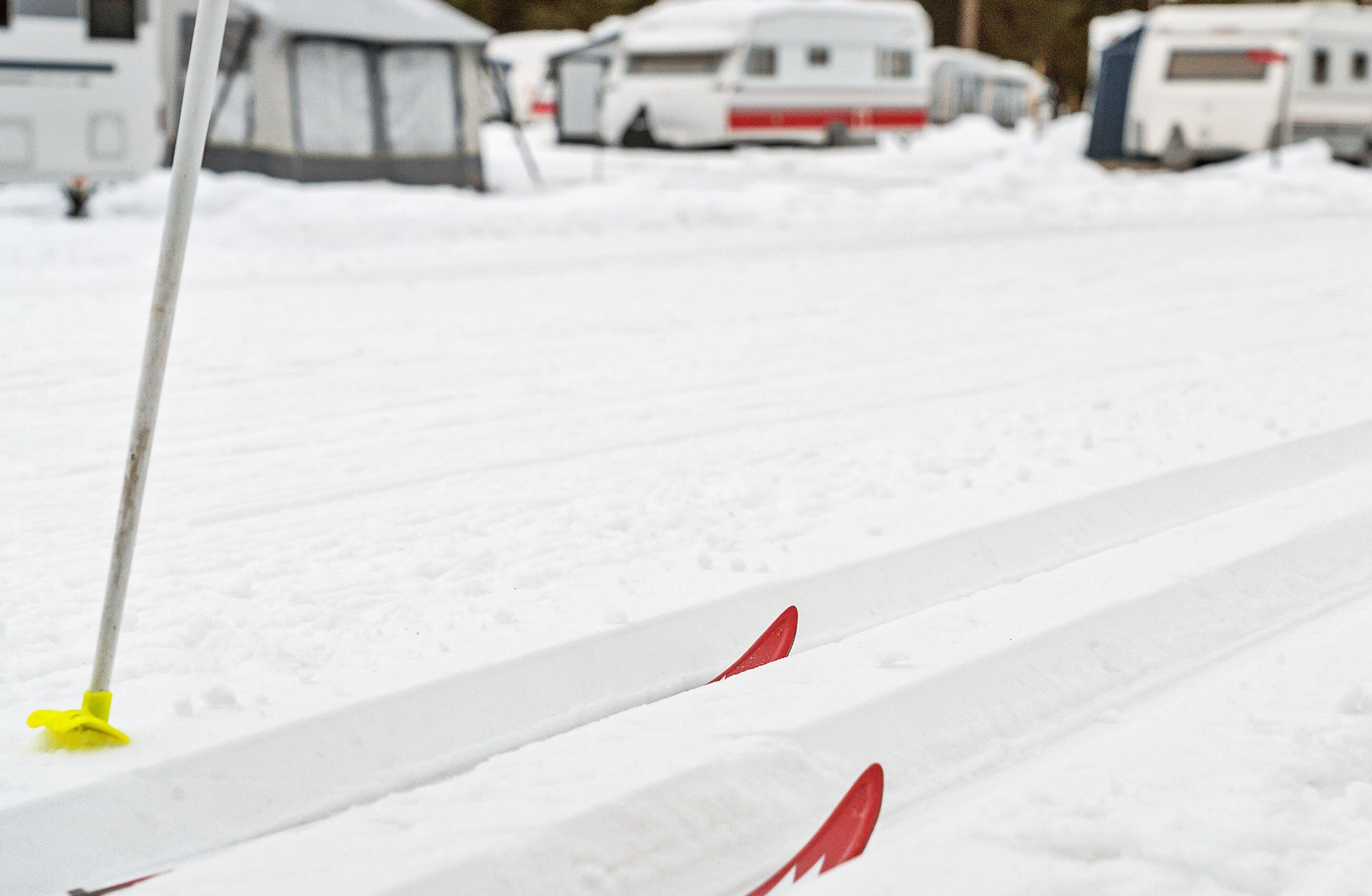 Un estacionamiento nevado con un vehículo blanco y un objeto amarillo al frente.