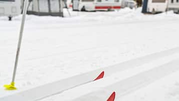 Un estacionamiento nevado con un vehículo blanco y un objeto amarillo al frente.