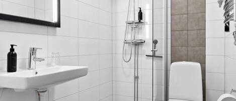 A modern bathroom with a white sink, toilet, and shower.
