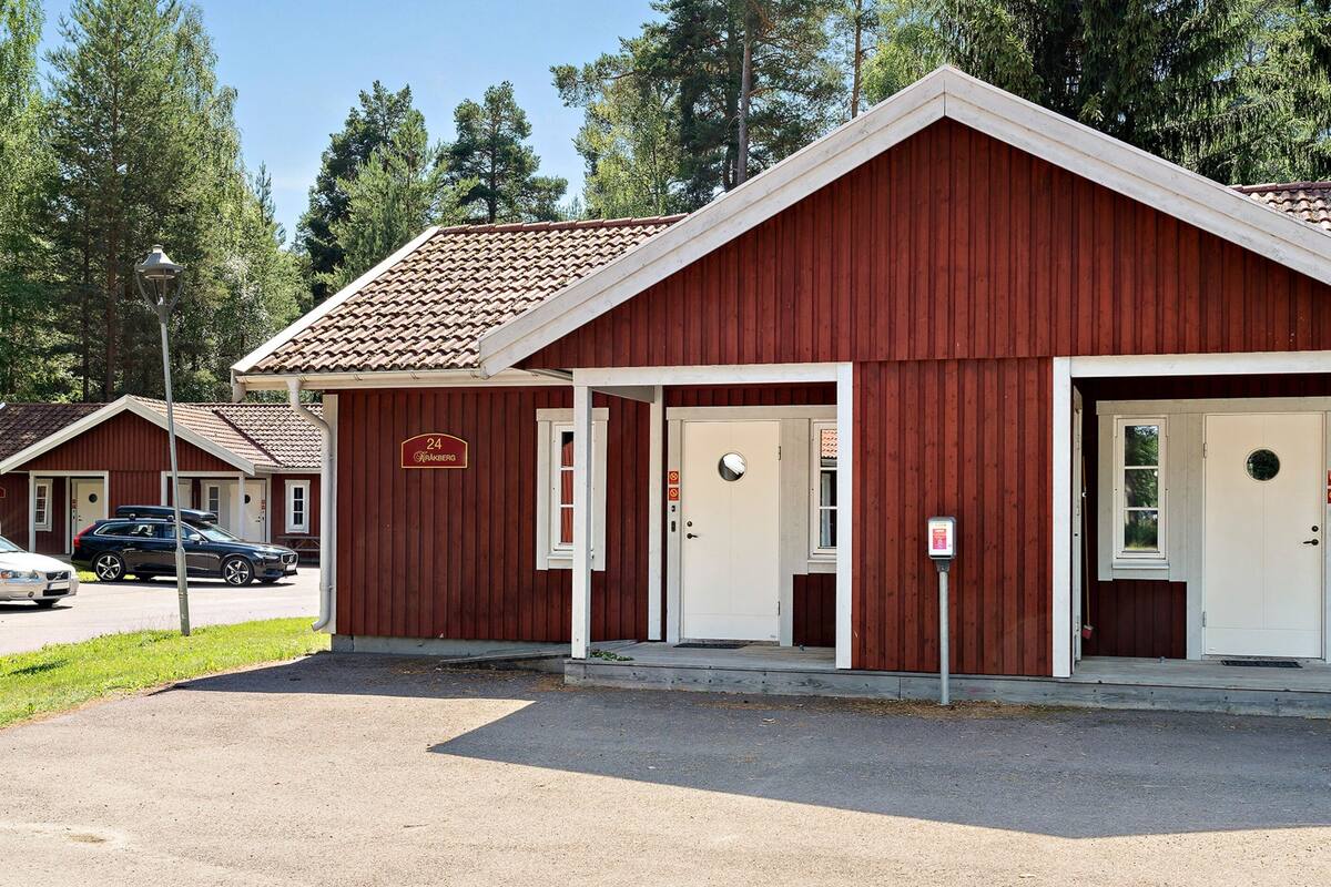 A red building with two white doors, a sign above the left door, and a lamp post in front.