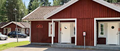A red building with two white doors, a sign above the left door, and a lamp post in front.