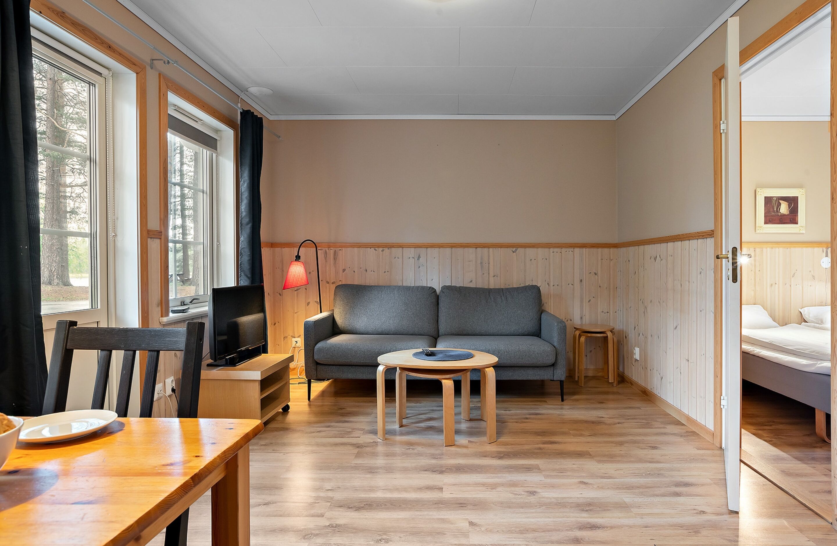A cozy room with a sofa, a small round table, a TV, and a bed.