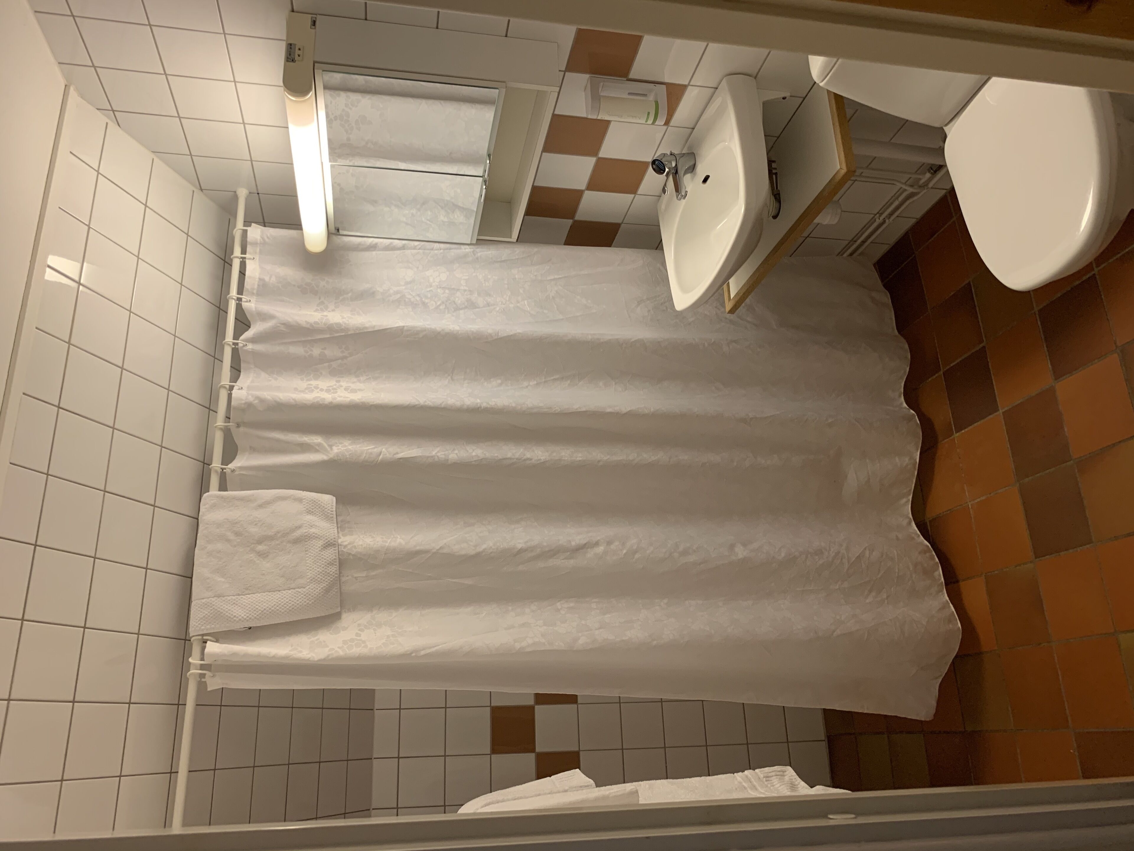 A bathroom with a shower curtain, a sink, a mirror, and a toilet.