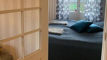 Una habitación con una cama, una ventana con cortinas y suelo de madera.