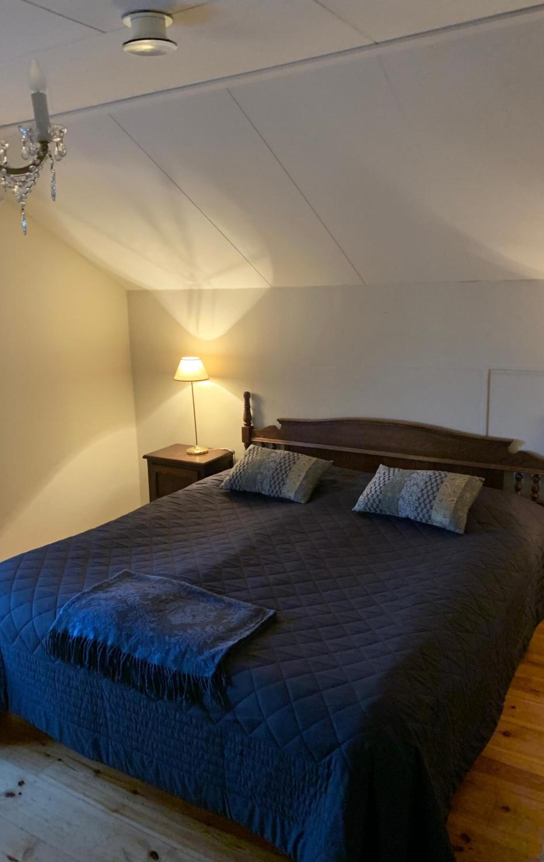 Un dormitorio con una cama grande, una mesita de noche, una lámpara y un candelabro.