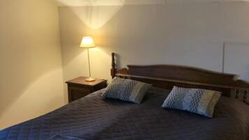 Un dormitorio con una cama grande, una mesita de noche, una lámpara y un candelabro.