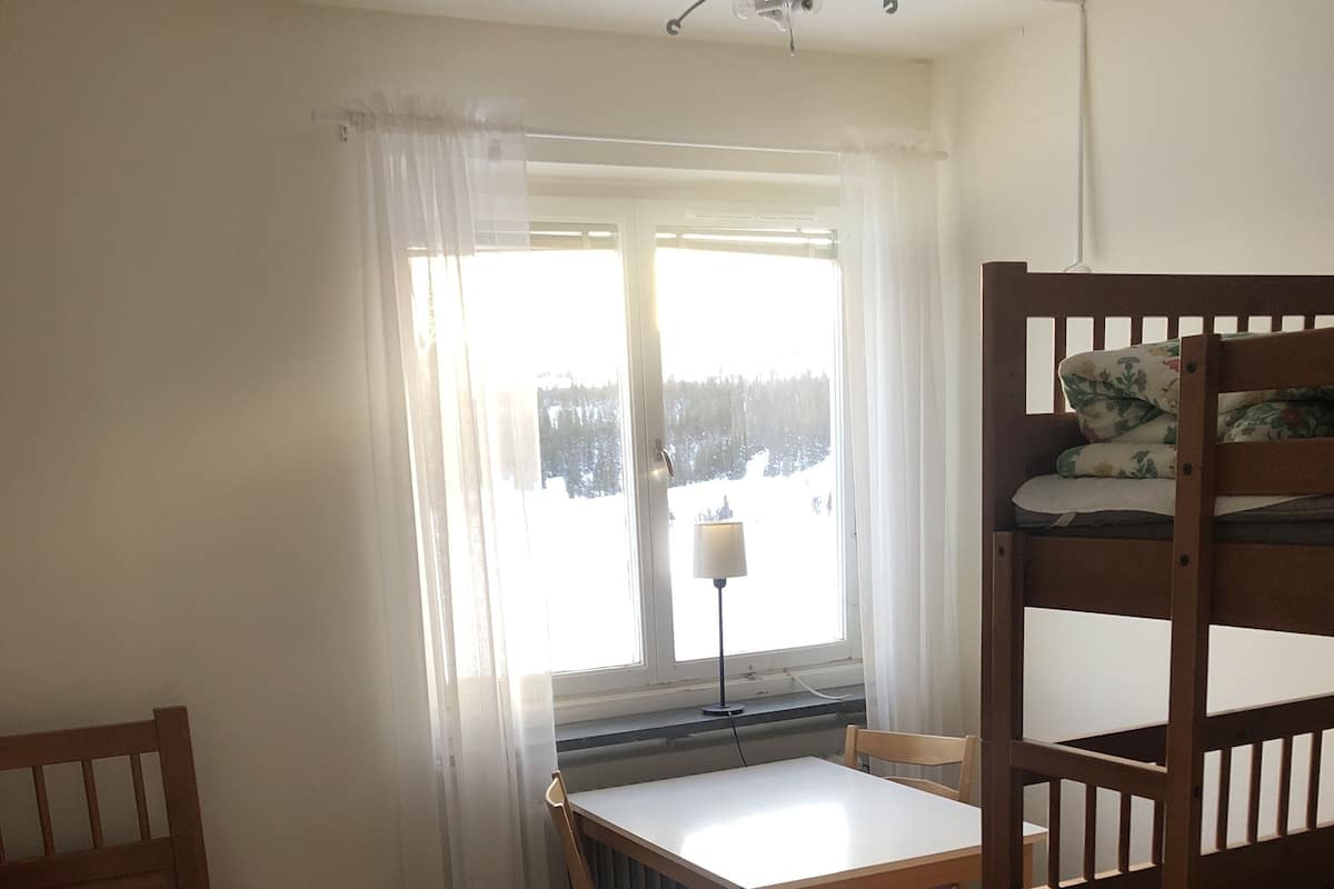 Une chambre avec un lit superposé, un lit simple, une table et une chaise.