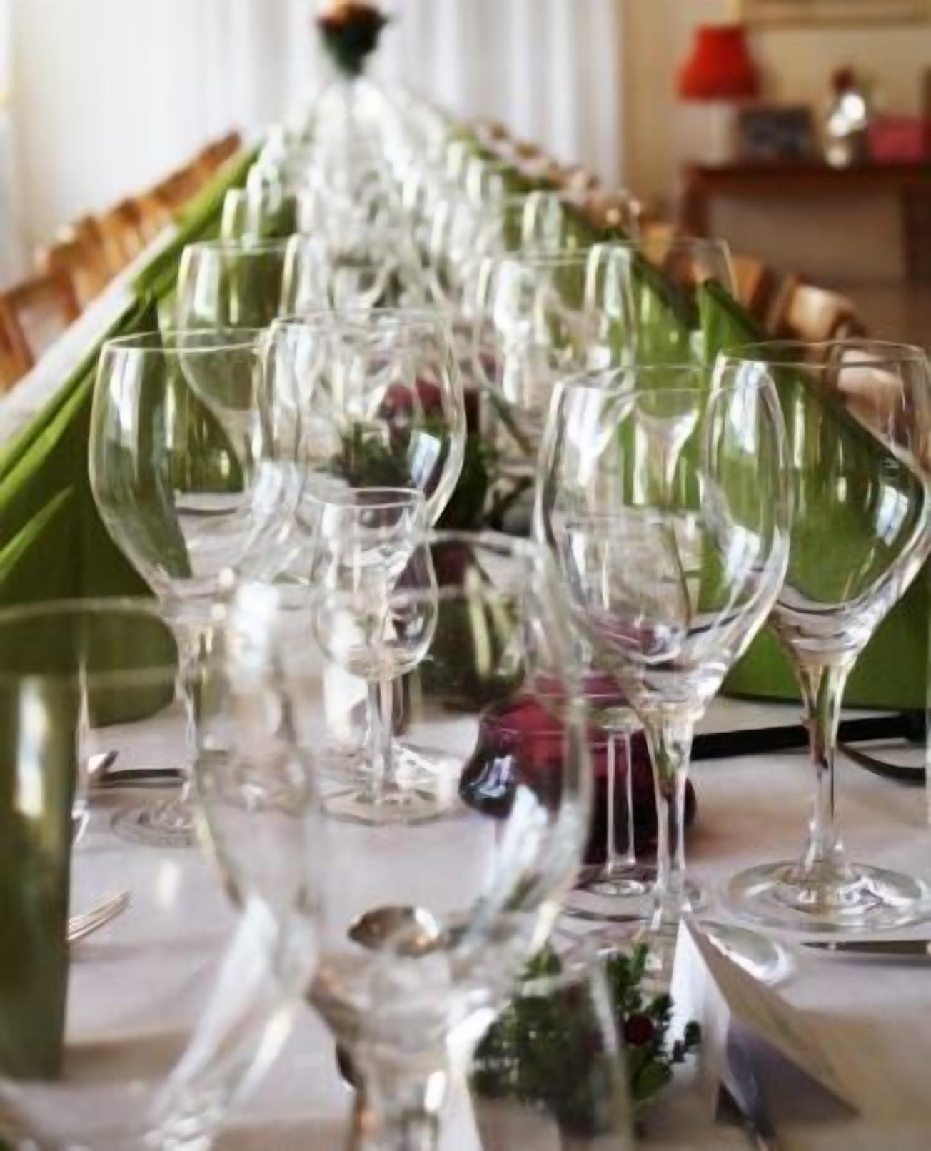 A long table set with multiple wine glasses and a bottle, likely for a formal event.