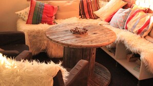 Eine gemütliche Sitzecke mit einem runden Holztisch, weichen weißen Kissen und bunten Zierkissen.
