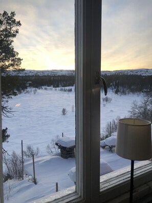 A view through a window of a snowy landscape with a lamp on the windowsill. - Storliens Fjällgård  - Hostel (Storlien)