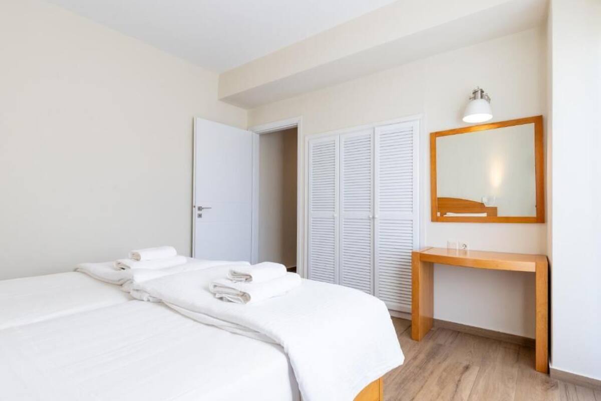 A bedroom with a bed, a wooden bedside table, a mirror, and a wardrobe.