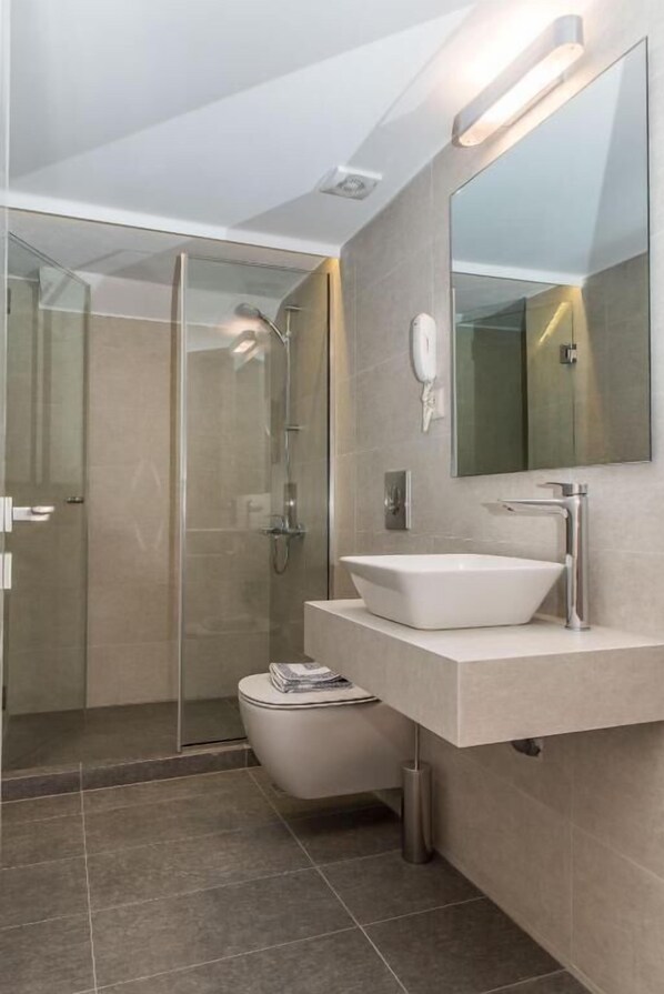 Une salle de bain moderne avec une douche à parois de verre, un lavabo blanc et un grand miroir.