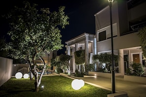 A modern building with a well-lit courtyard, featuring a tree and spherical light fixtures. - Creta Elena (Chania)