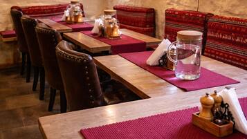 A restaurant with wooden tables and red cushioned benches.