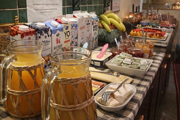 Una mesa de buffet con diversos alimentos, como frutas, salsas y productos lácteos.