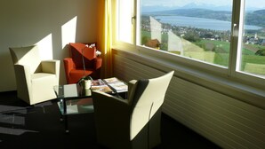 A modern room with two chairs, a table, and a view of a lake and mountains.