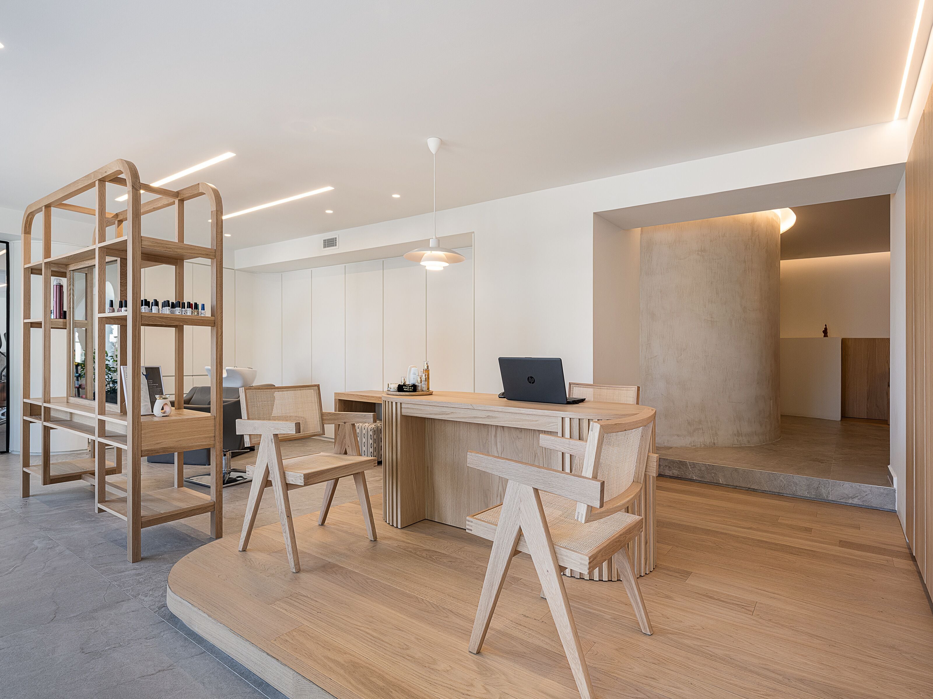 A modern, minimalist office space with a wooden desk, chairs, and a laptop.