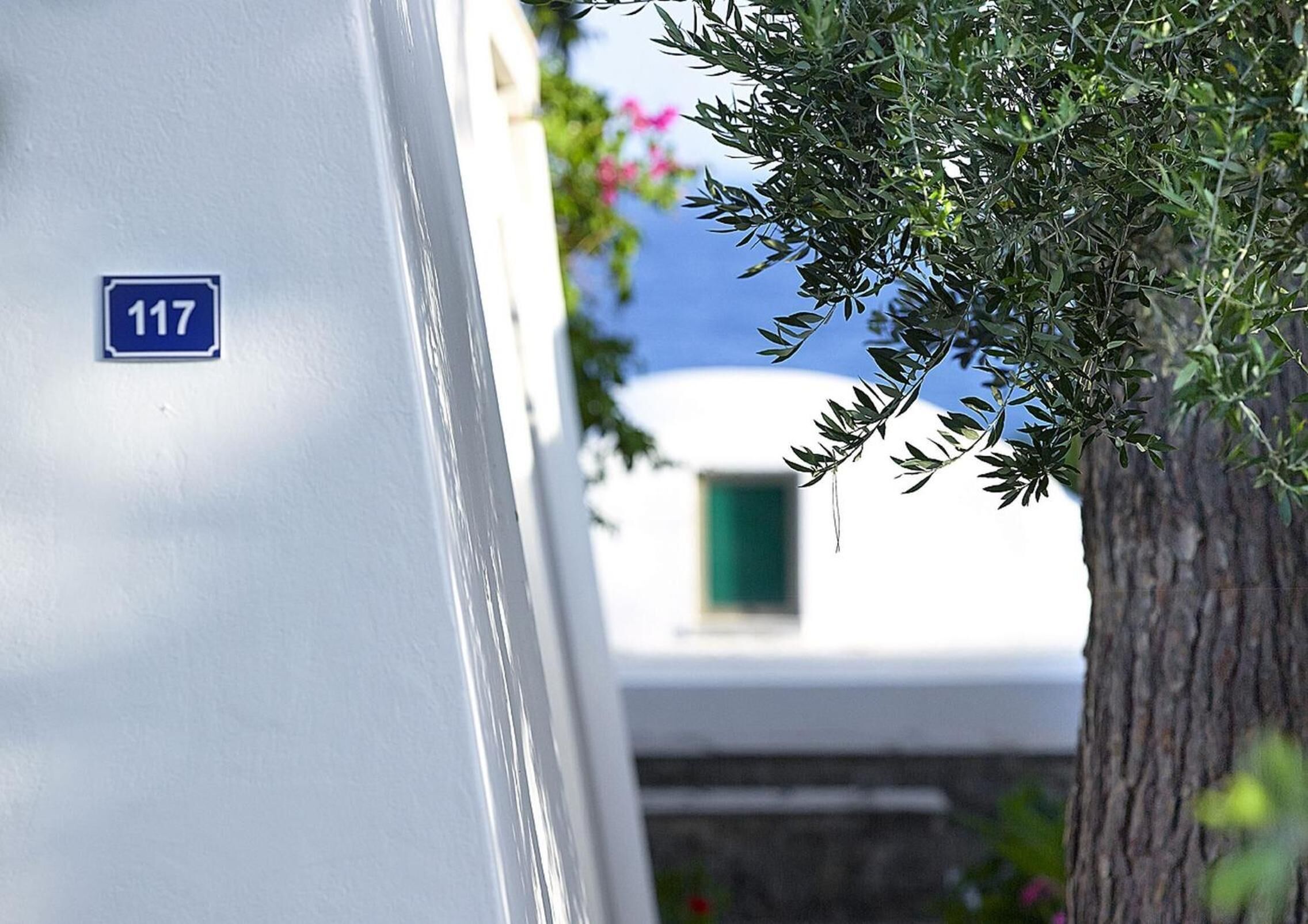 Un edificio con fachada blanca y un letrero azul que indica el número 117.