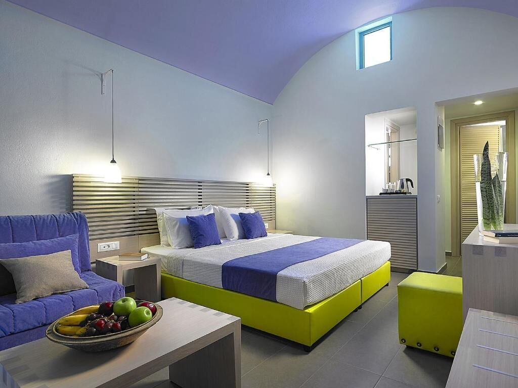 Un dormitorio moderno con cama, sofá, mesita de noche y frutero.