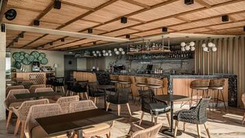 A modern bar area with wicker furniture, a bar counter, and a ceiling with wooden beams.