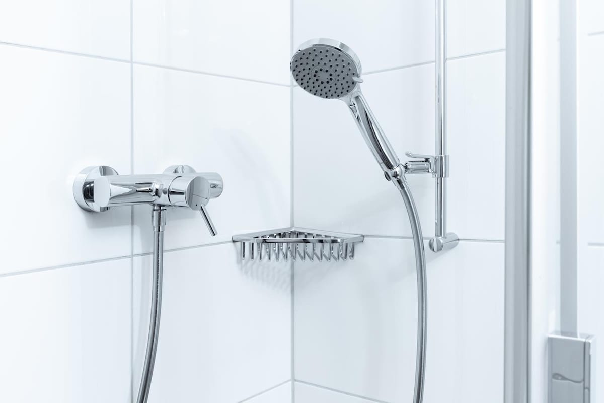 Ducha moderna con cabezal de ducha de mano y cabezal de ducha empotrado, ambos con acabados cromados.