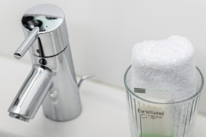Un baño con un grifo moderno y un recipiente de vidrio con una toalla blanca.