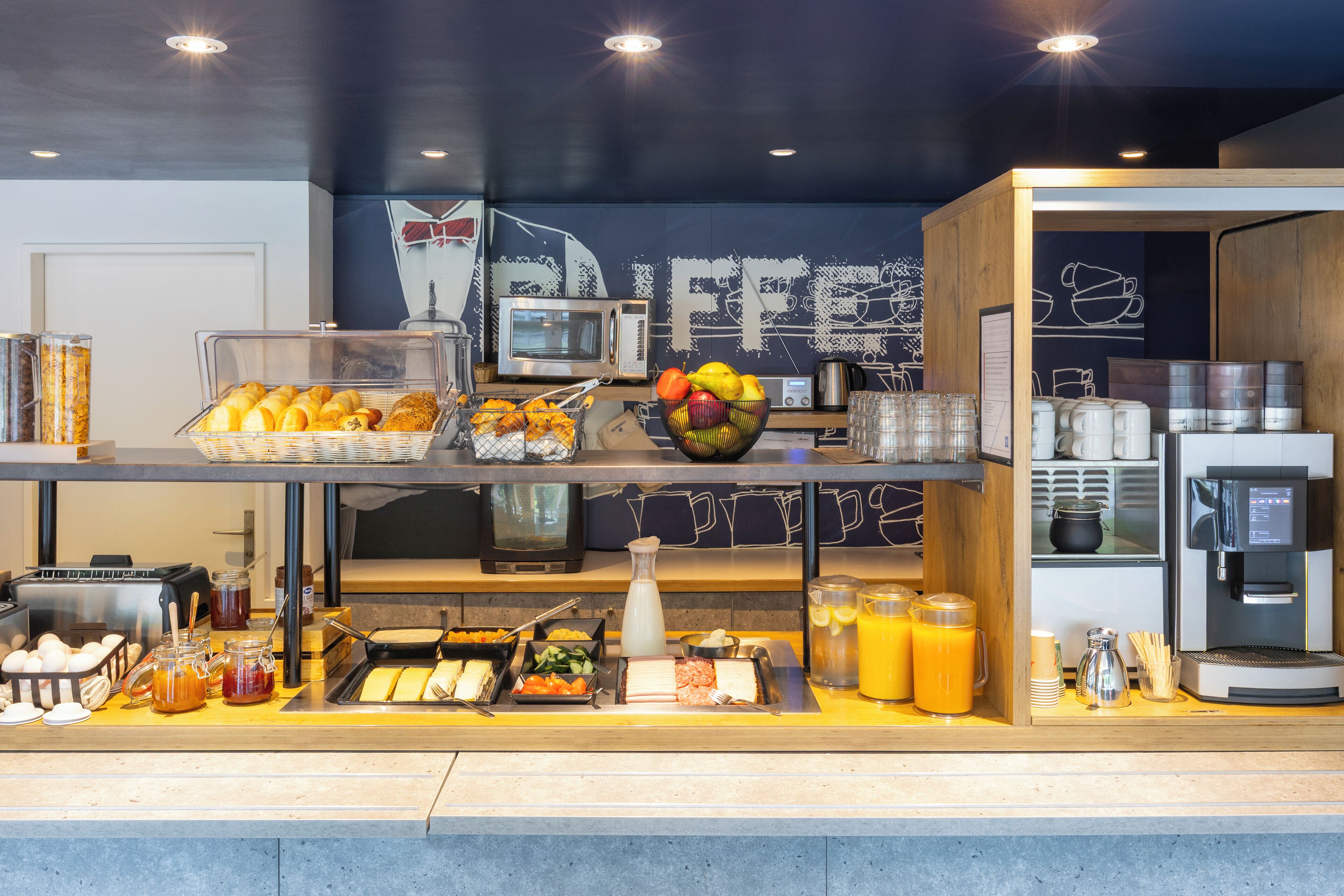 A breakfast buffet with various food items, a coffee machine, and a microwave.