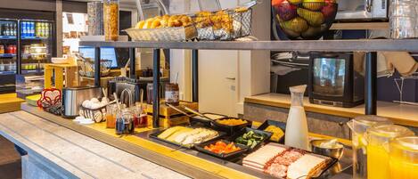 A buffet area with various food options, a microwave, and a fruit bowl.