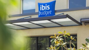 A building with a blue sign reading "ibis budget" and a glass awning.