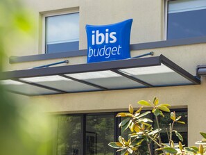 A building with a blue sign reading 'ibis budget' and a covered entrance. - ibis budget Basel Pratteln (Pratteln)