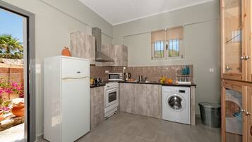 A compact kitchen with a refrigerator, stove, microwave, and washing machine.