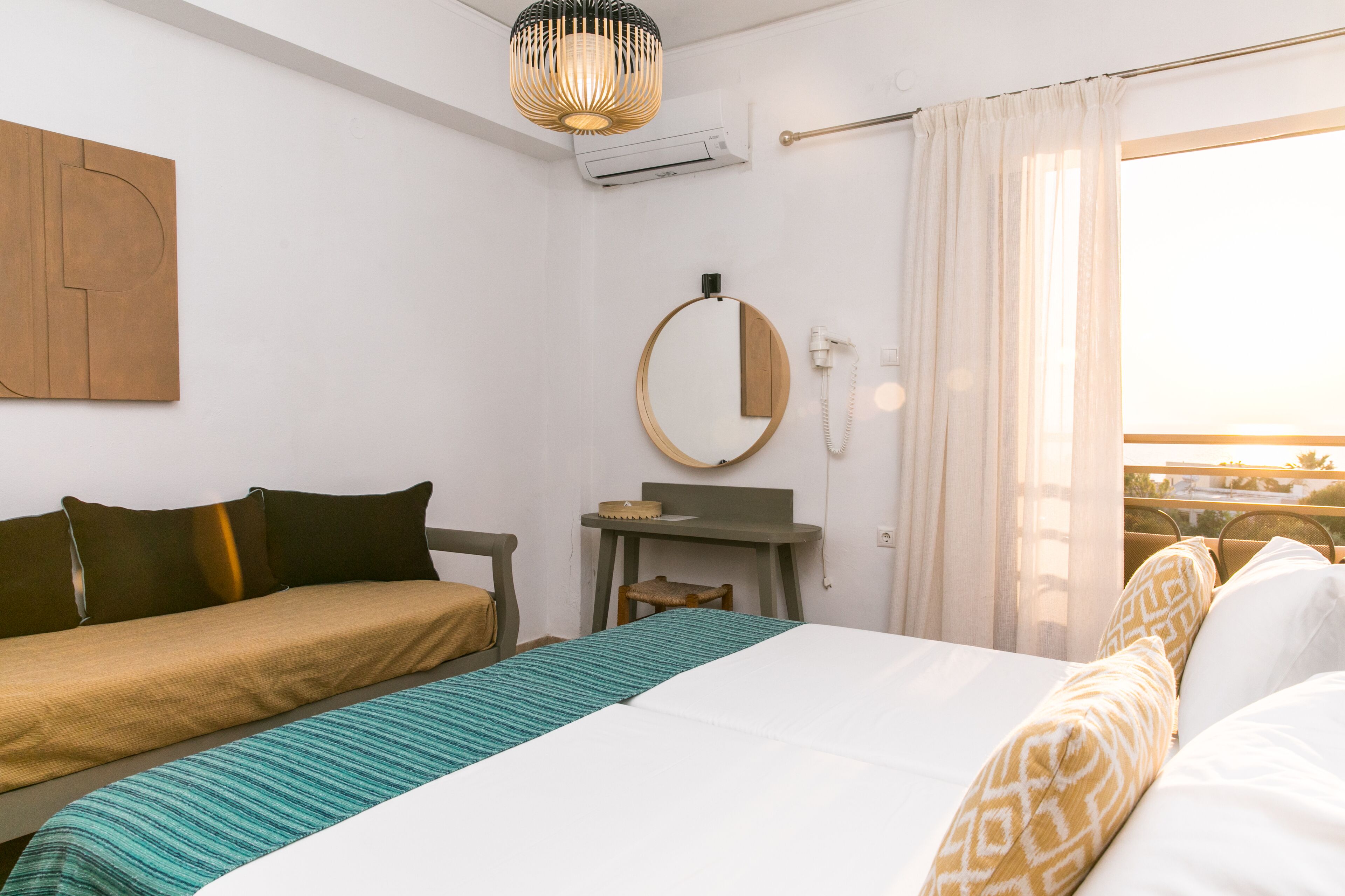 A bedroom with a bed, a desk, a chair, a mirror, and a window with curtains.