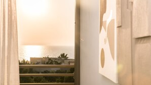 A view through a window with a curtain, revealing a building and a body of water. - Creta Vitalis (Chania)