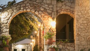 A stone archway with potted plants and a warm light source. - Creta Vitalis (Chania)