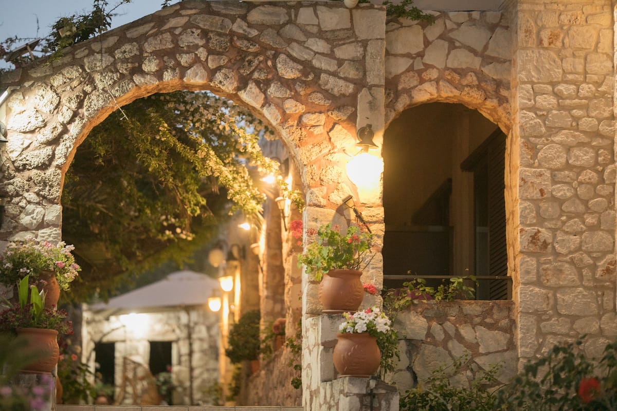 A stone archway with potted plants and a warm light source.