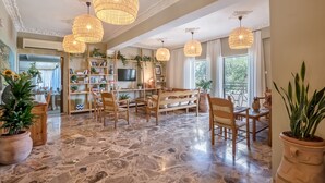 A spacious living room with a marble floor, wooden furniture, and large woven light fixtures. - Creta Vitalis (Chania)