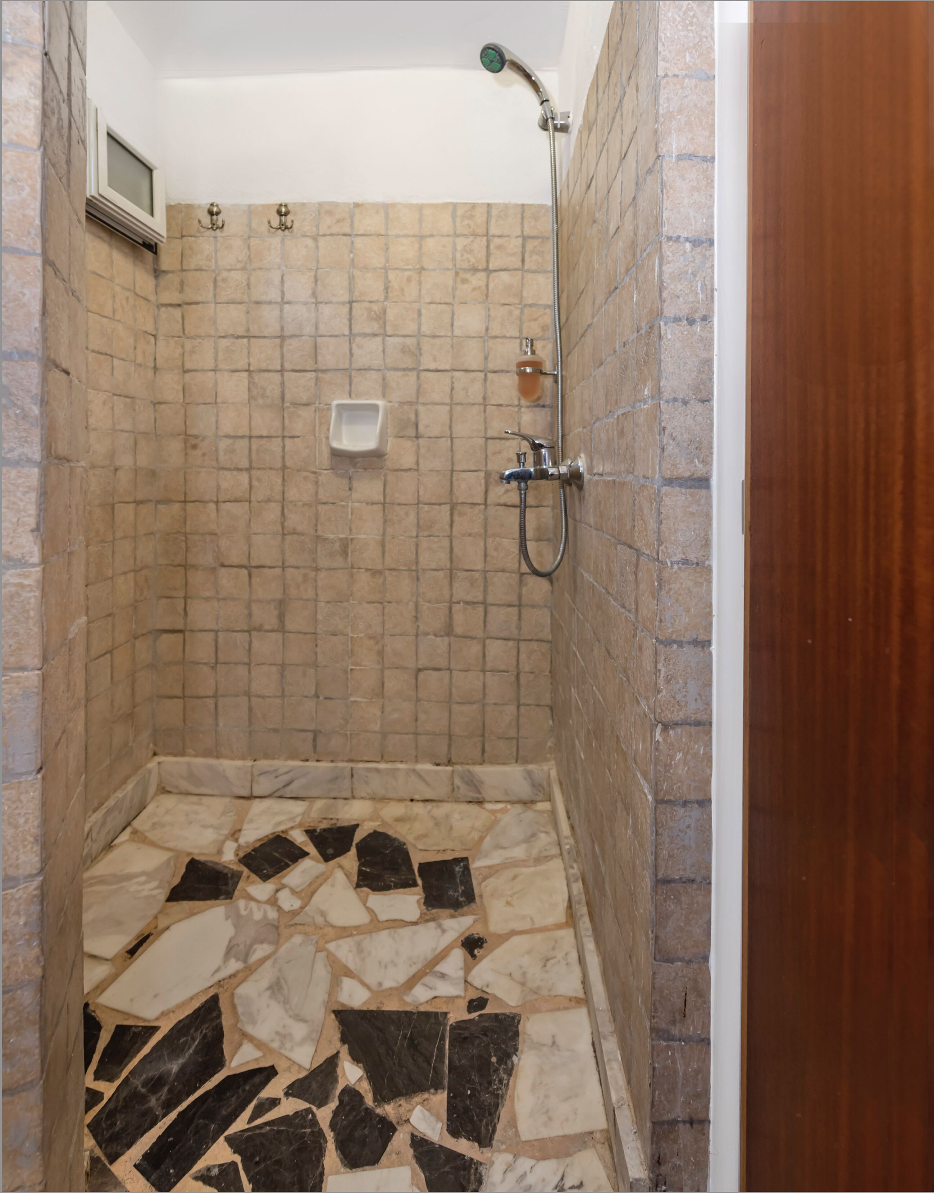 Ducha con piso de cerámica y cabezal de ducha manual.