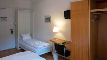 Une chambre d’hôtel avec deux lits, un bureau avec une lampe, une télévision et une armoire.