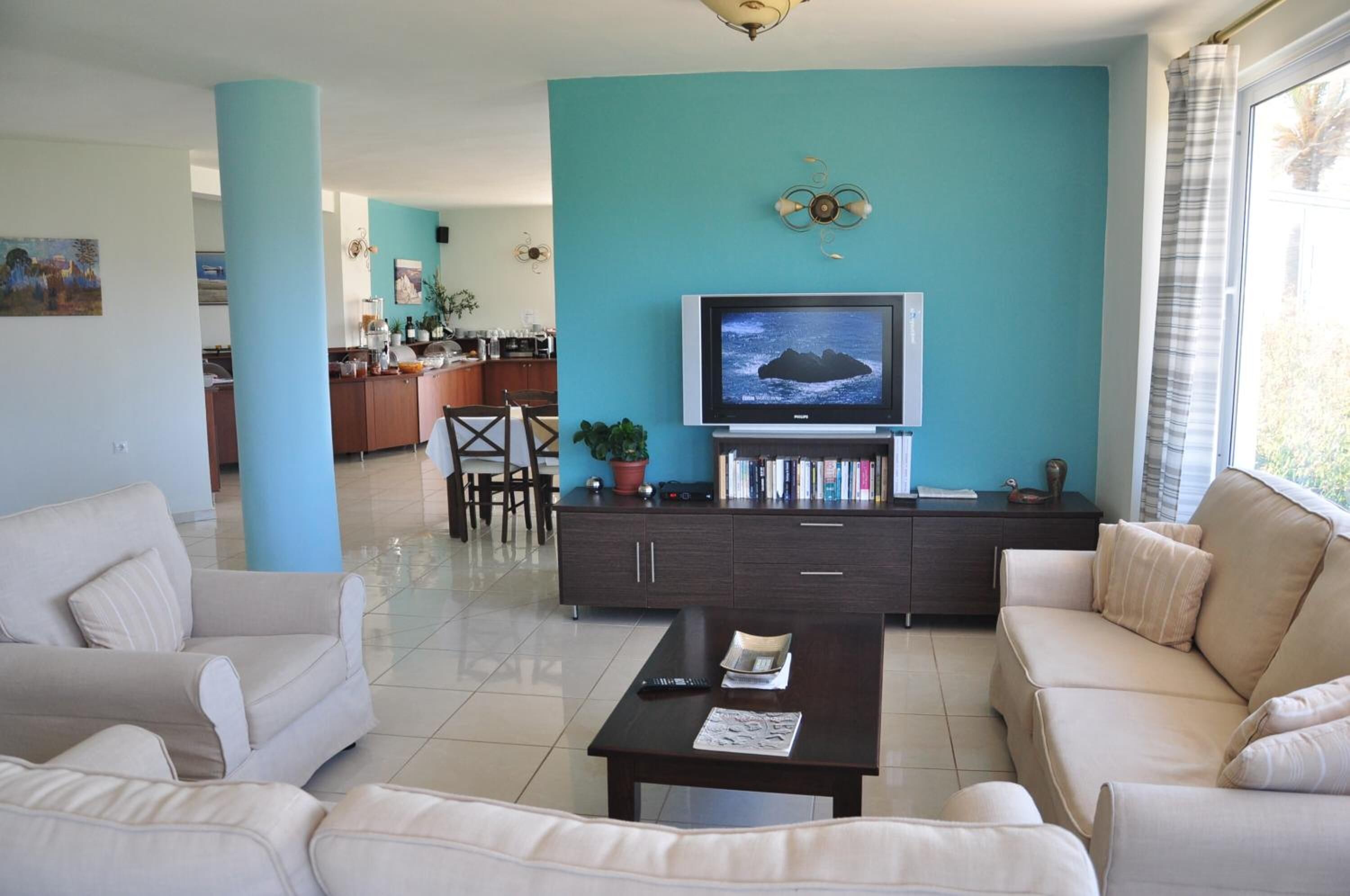 Un salon avec un mur d’accent de couleur turquoise, un téléviseur, une table basse et un canapé.