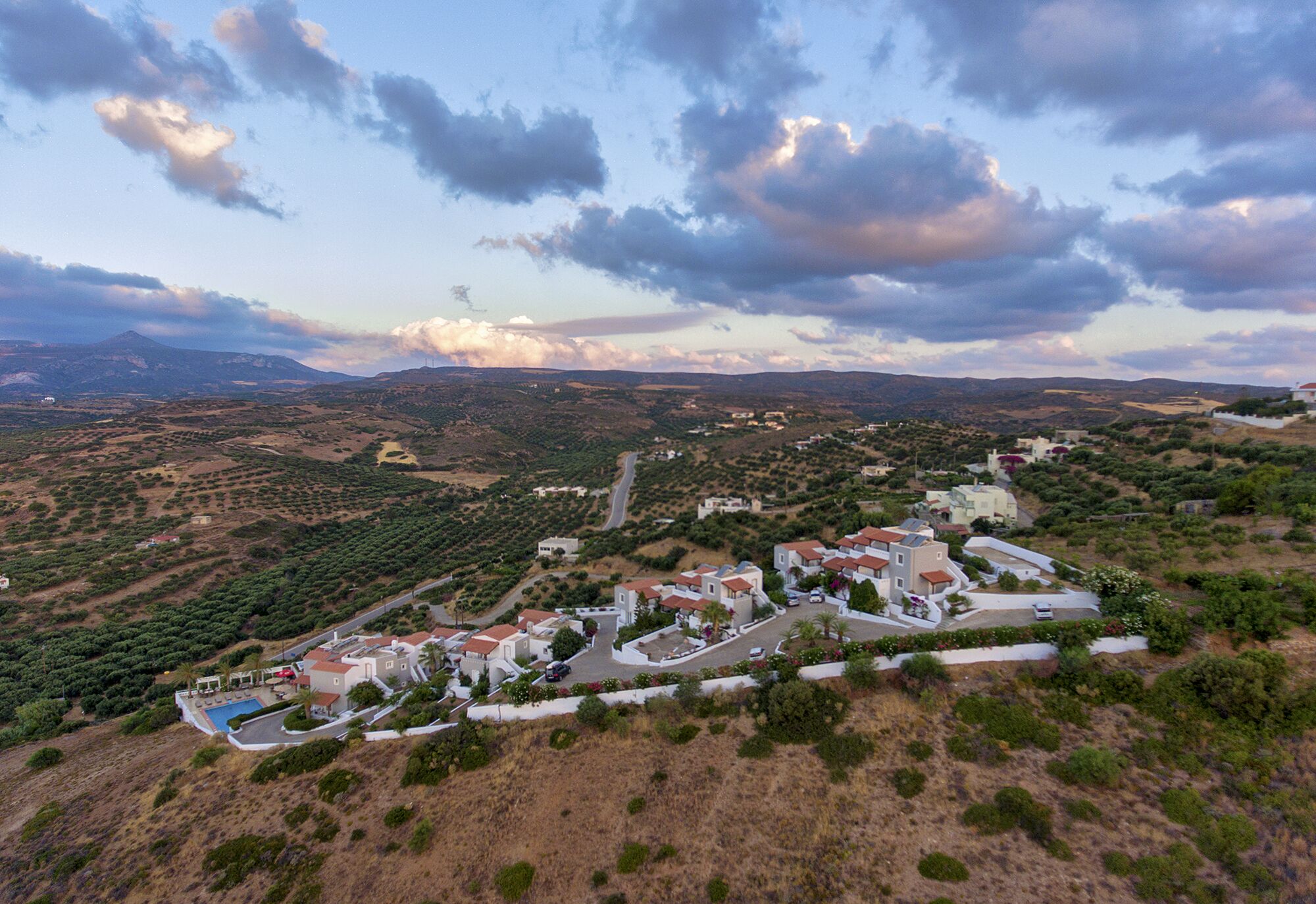 A coastal resort with villas, a swimming pool, and a winding road.