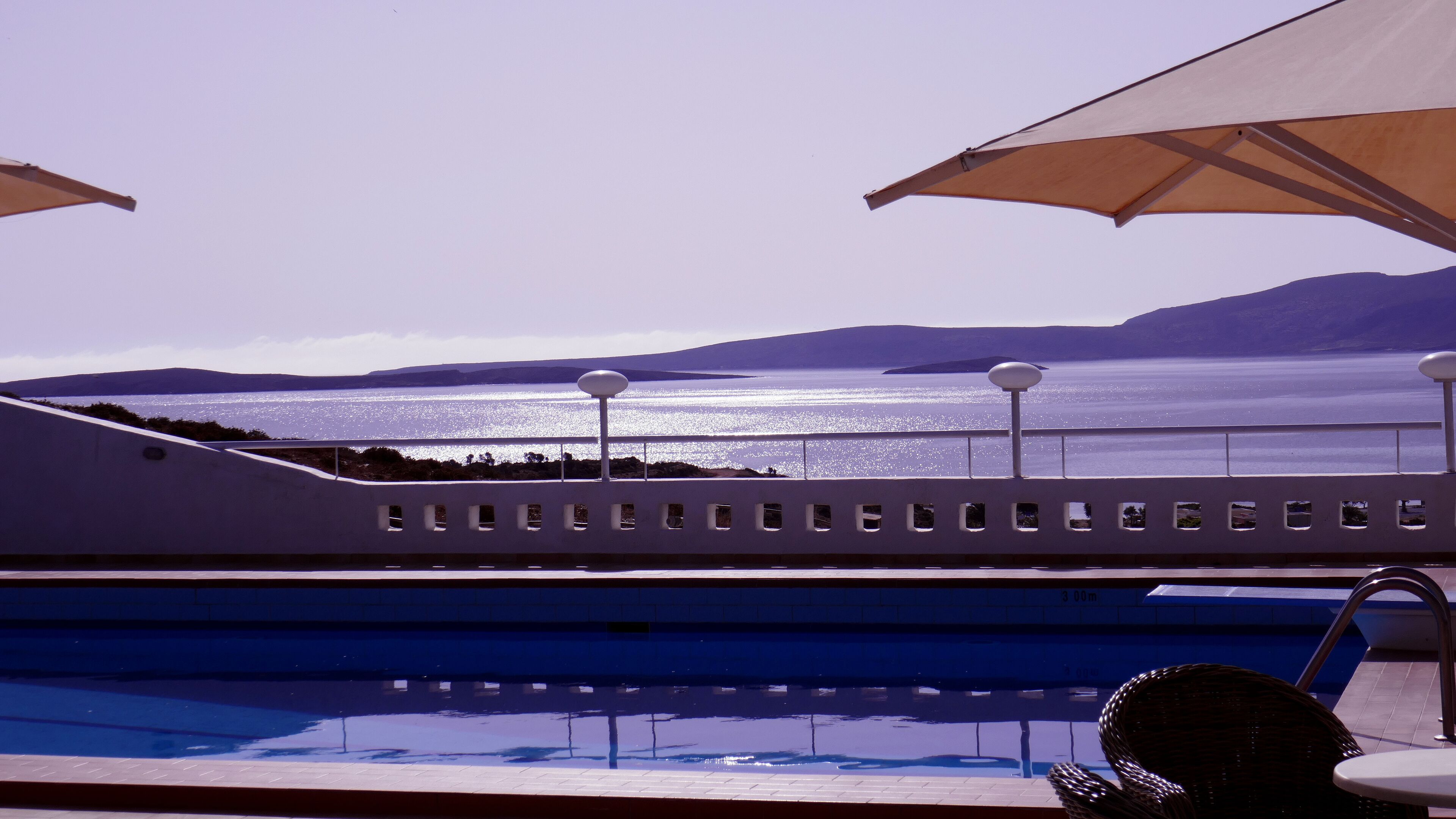 A pool with a view of the sea and mountains.