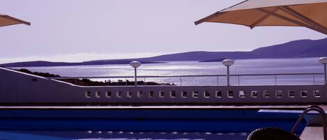 A pool with a view of the sea and mountains.