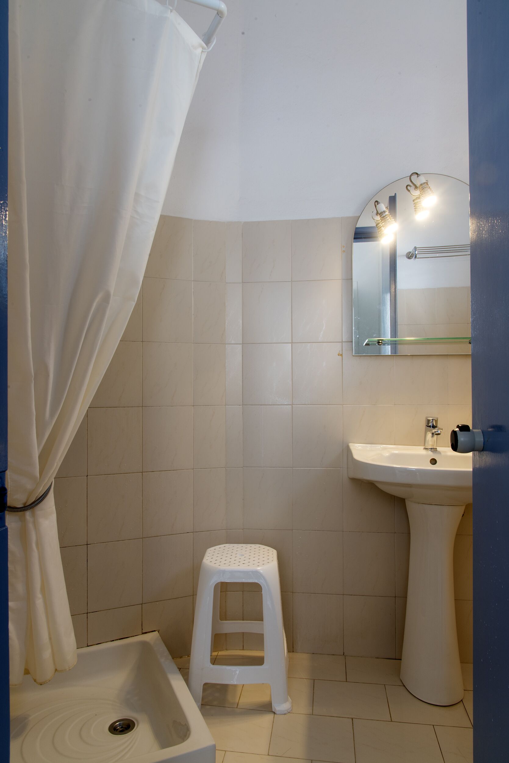Une salle de bain avec un lavabo, un miroir et un petit tabouret.