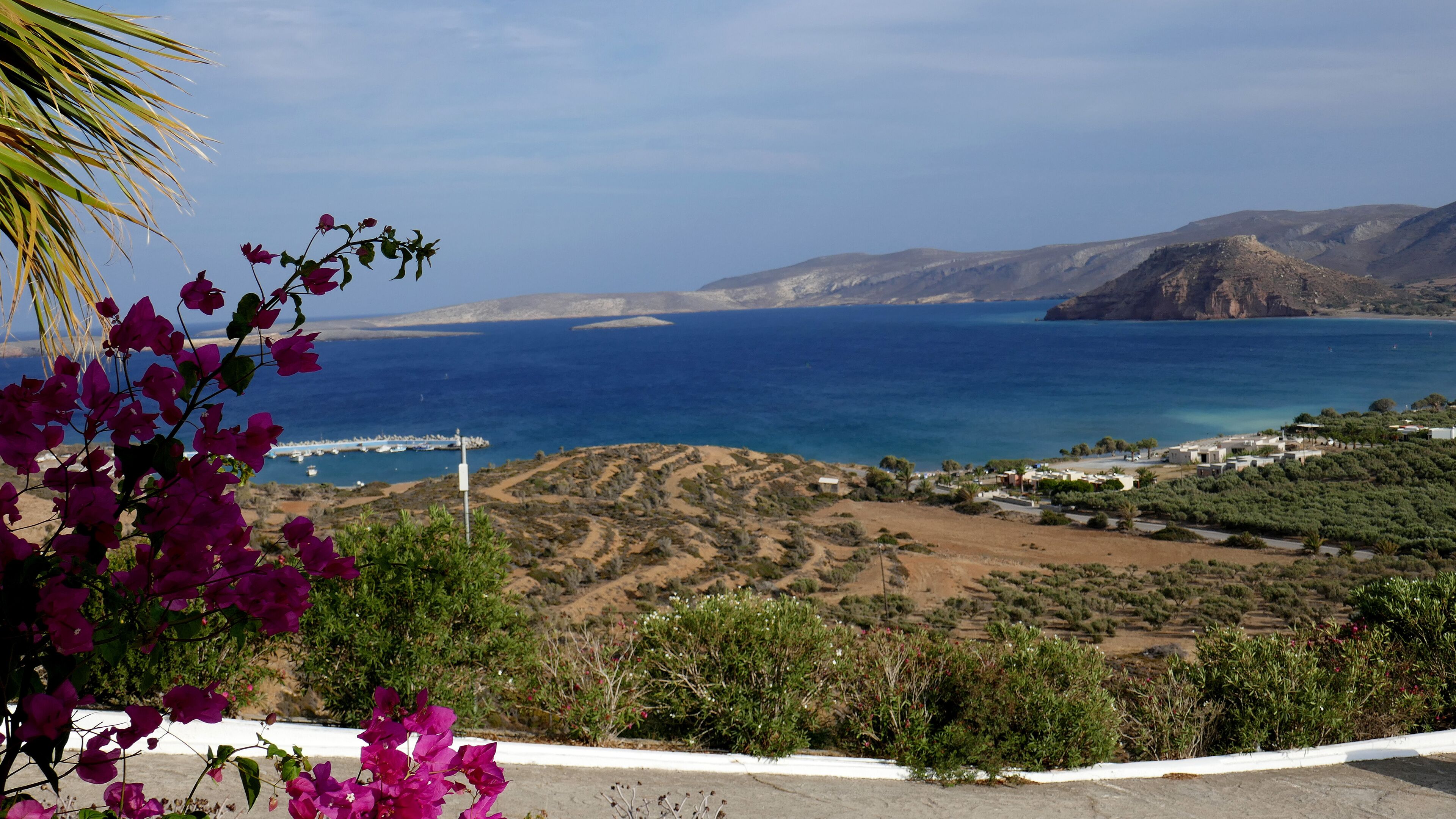 A coastal landscape with a view of the sea, a small settlement, and a road leading to the settlement.