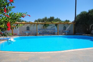 A clear blue swimming pool with a pergola and seating area. - Marina Village (Sitia)
