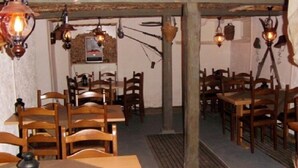 A restaurant interior with wooden tables and chairs, hanging light fixtures, and a rustic decor. - Hotel & Restaurant Alpenrose (Innertkirchen)