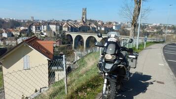 Une moto est garée sur un trottoir, offrant une vue sur une ville, avec un pont et une église en arrière-plan.