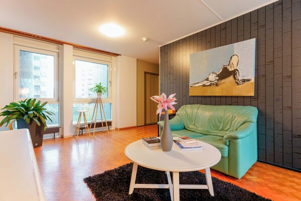 Uma sala de estar moderna com um sofá verde, uma mesa de centro branca e um quadro na parede.